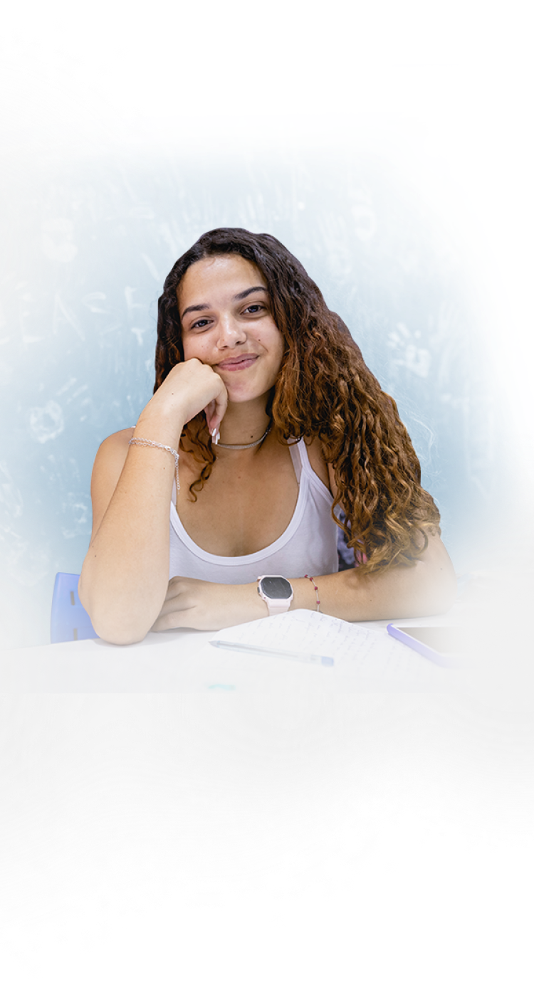 Mulher de regata branca e cabelo cacheado apoiando o rosto com o braço.